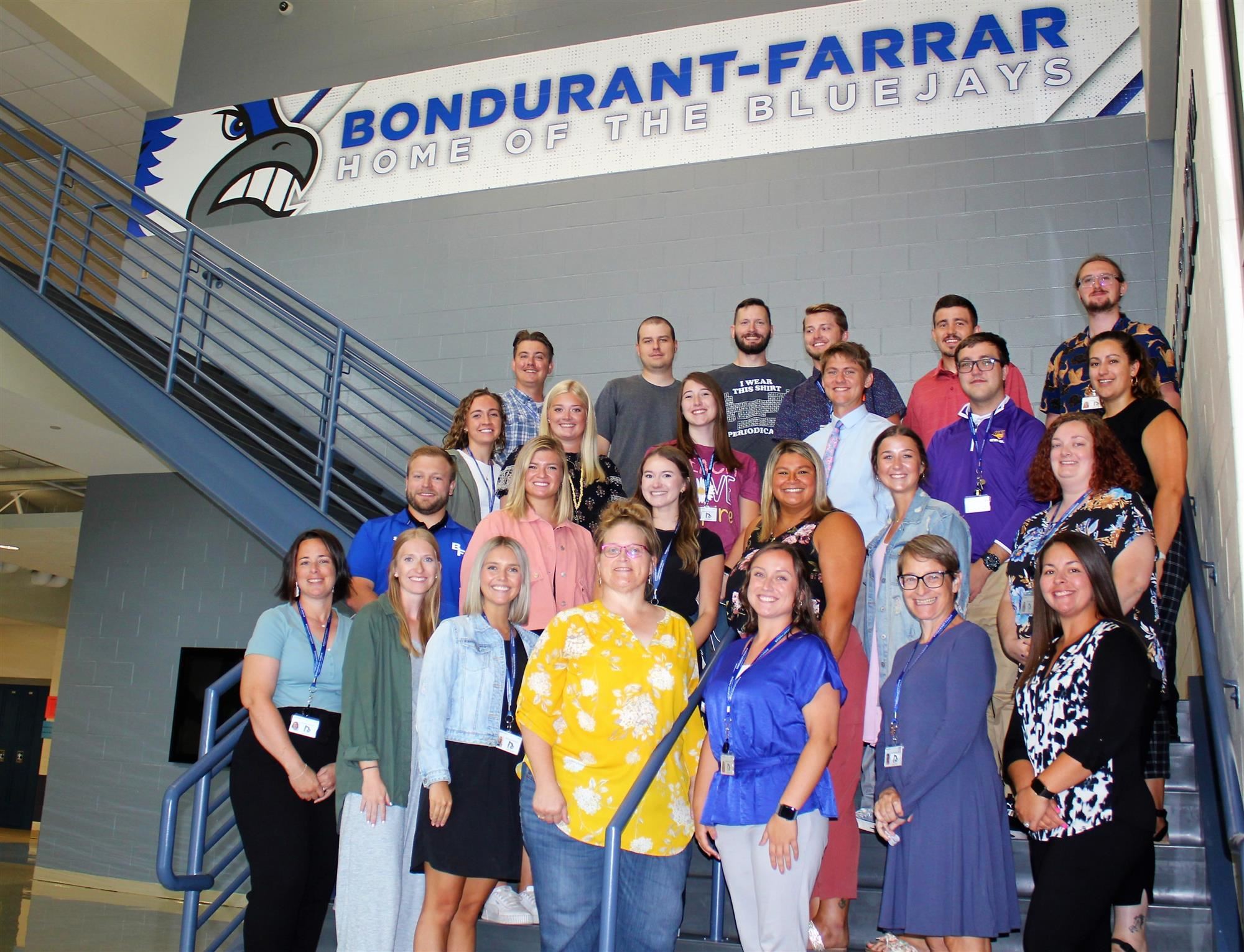 New teachers stand for picture on main stairway of the high school