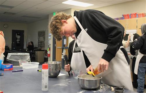 Student measuring honey over a bowl